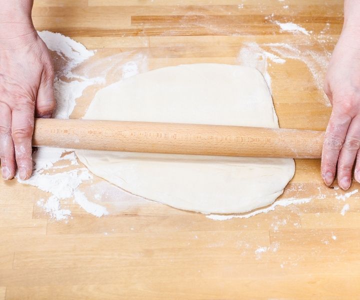 dough being rolled with rolling pin