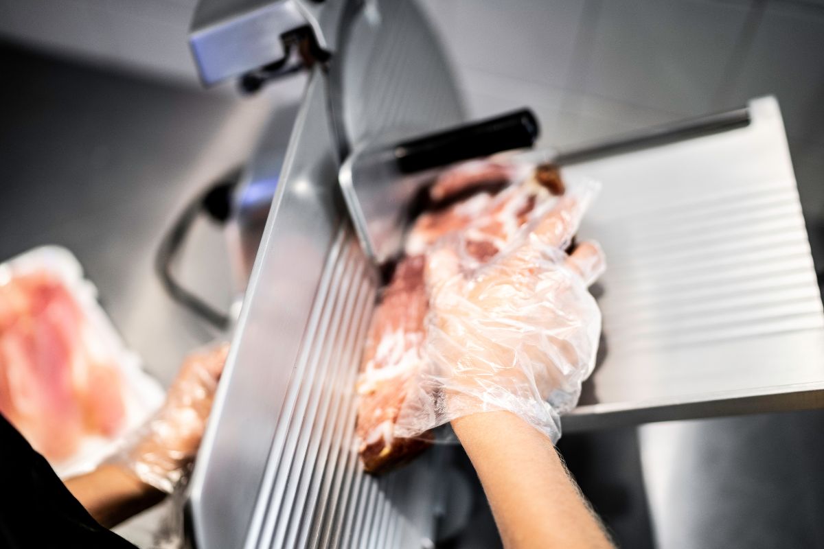 Slicing a piece of ham  in the meat slicer